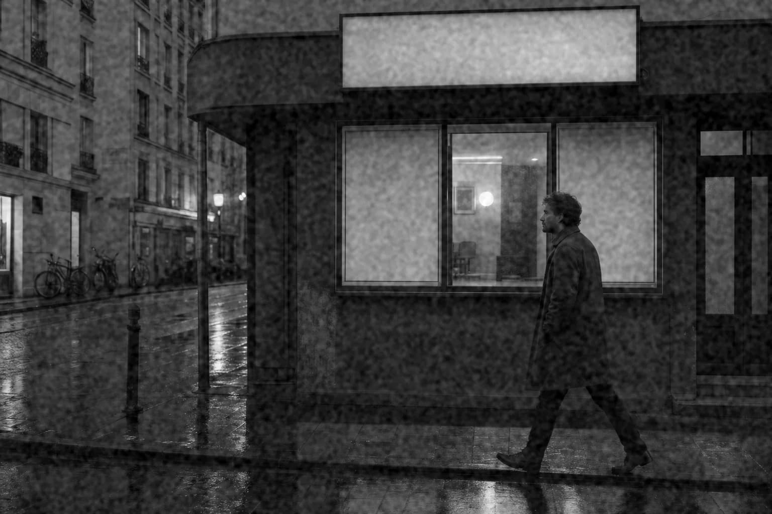 Black-and-white rainy street with medium, slightly soft grain and moderate contrast in the style of HP5 Plus