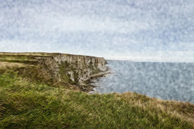 Coastal cliffs with a coarse Super 8-scale film grain overlay blended in Overlay mode